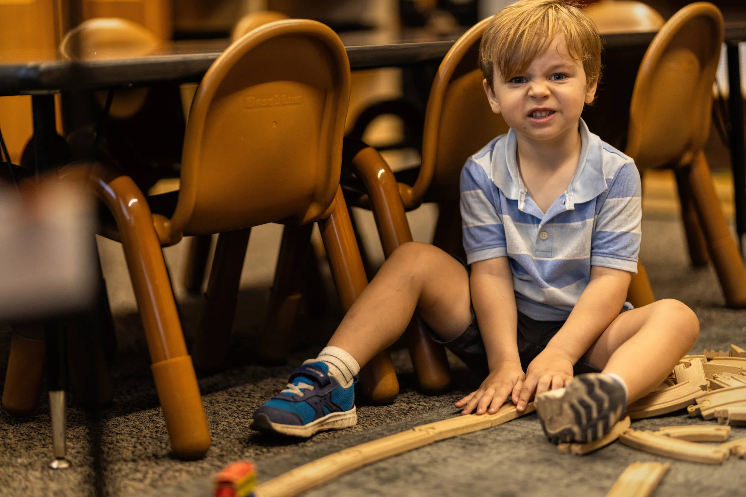 A child building with wooden train tracks in a Strauss ECE classroom