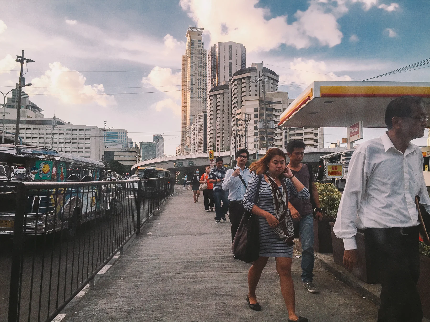 City life: pedestrians walking down the sidewalk after work. Many of them are headed to the bus stations all around. On the left you don't see a 7 year old girl begging for money as she knocked on people's car windows. 