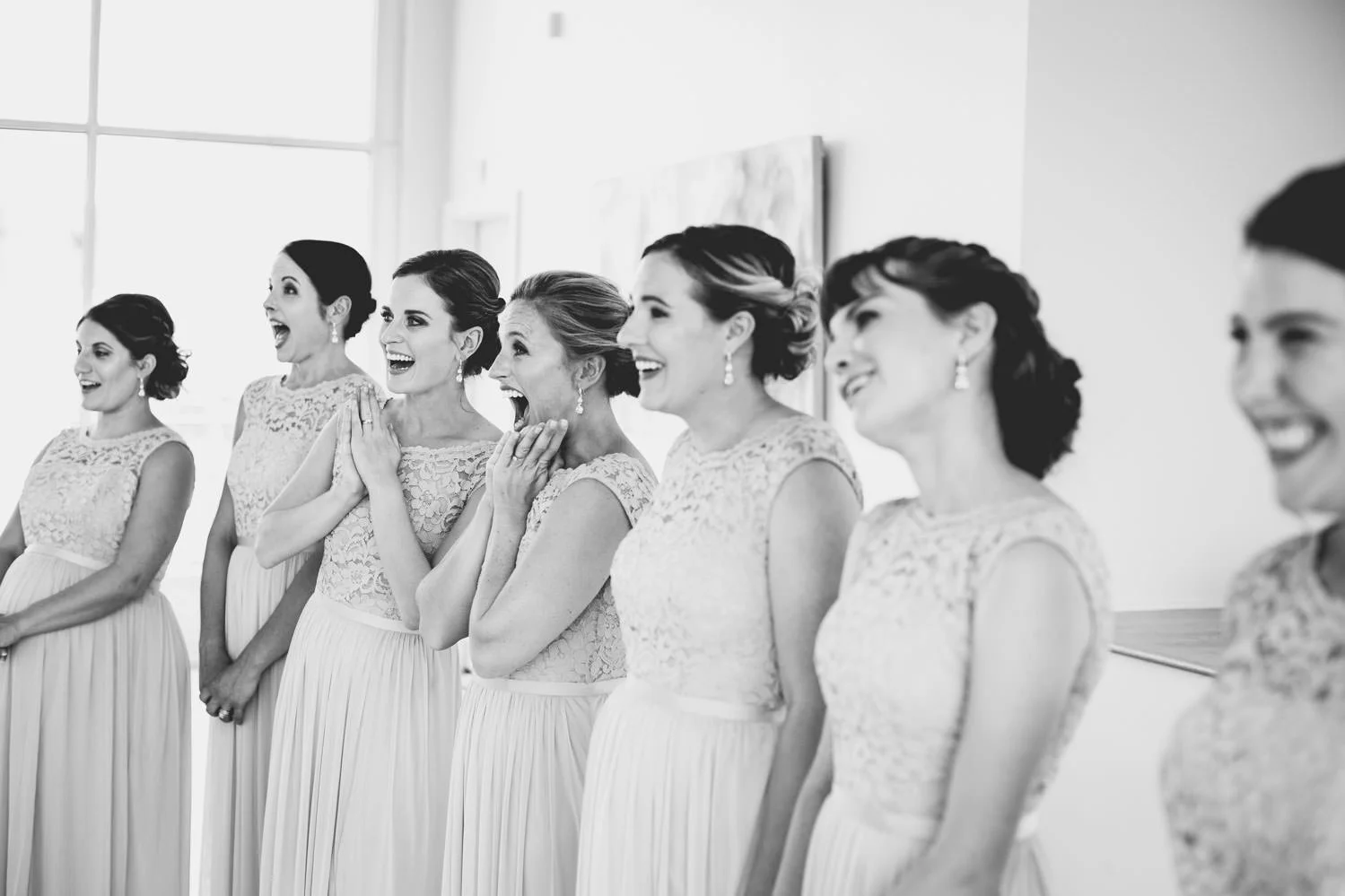 Photo taken in the Glass Box in Raleigh, North Carolina. The Glass Box is owned by The Stockroom at 230 wedding venue. The bridal party's jaws drop when they see their best friend in their wedding dress for the first!