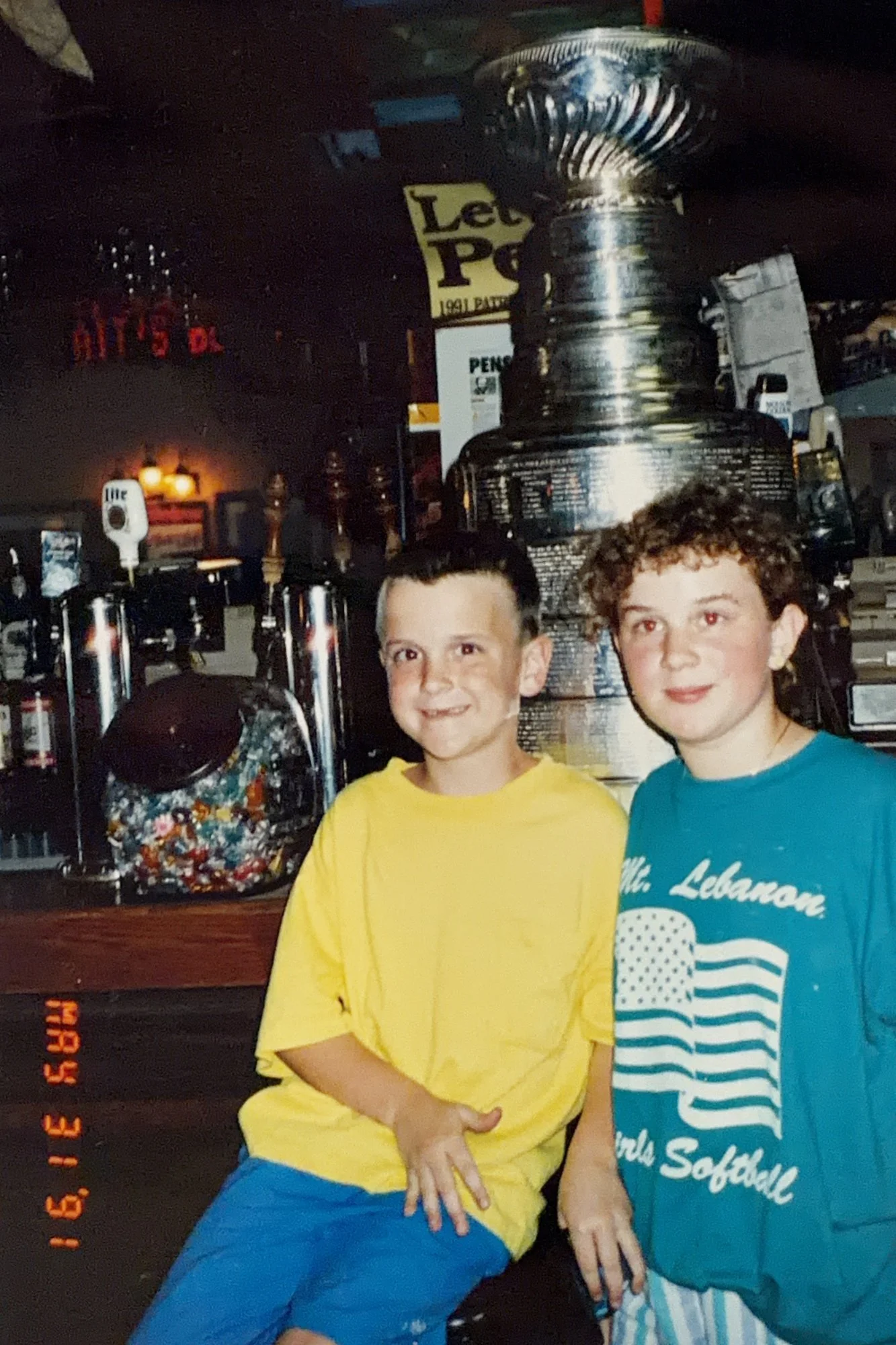 Keith Sheppard and his sister Kirstin as kids at The Saloon's bar in front of the Stanley Cup, with a 'Let's Go Pens' sign behind them, May 31, 1991