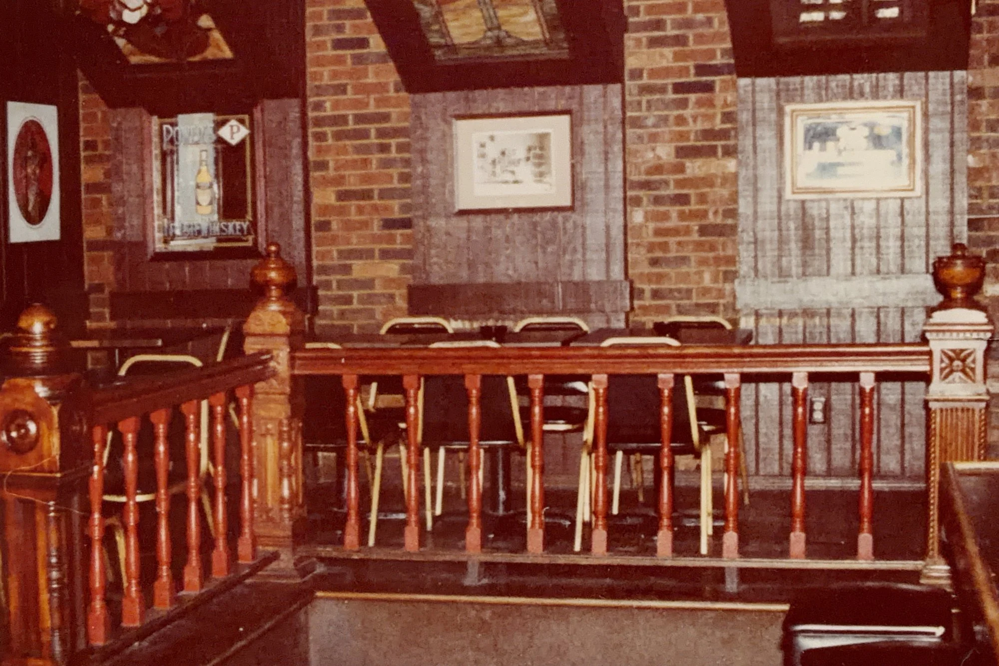 The Saloon's finished raised dining area with a turned-wood railing and brick walls