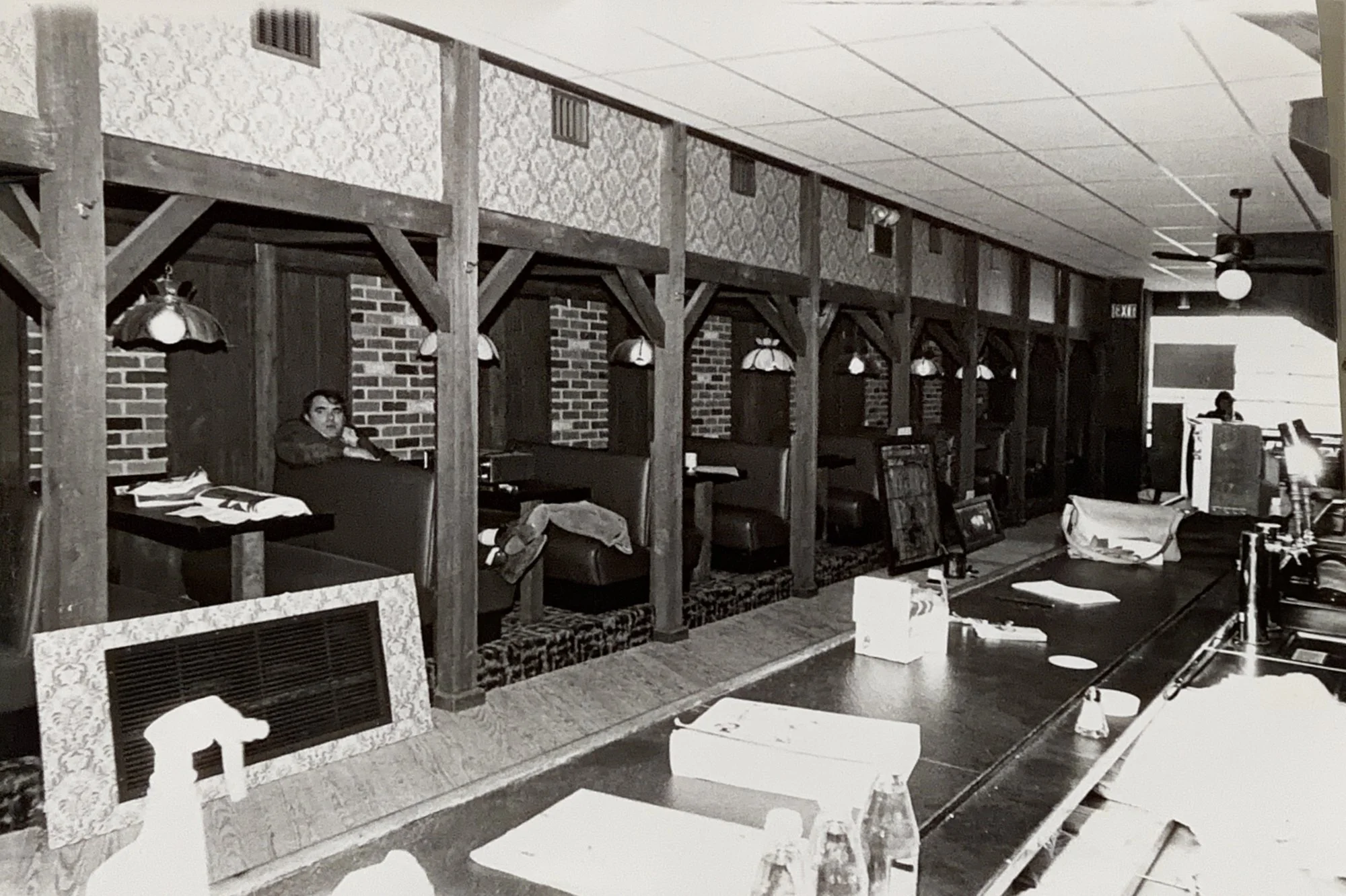 The Saloon's wooden booths and bar nearly finished during construction, with a man relaxing in a booth