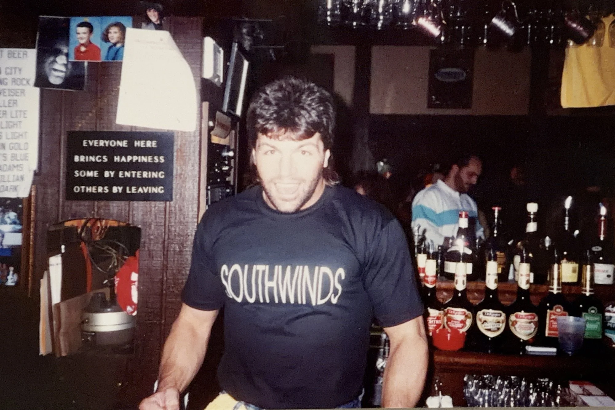 Pittsburgh Penguins winger Phil Bourque in a Southwinds T-shirt guest bartending behind The Saloon's bar, early 1990s