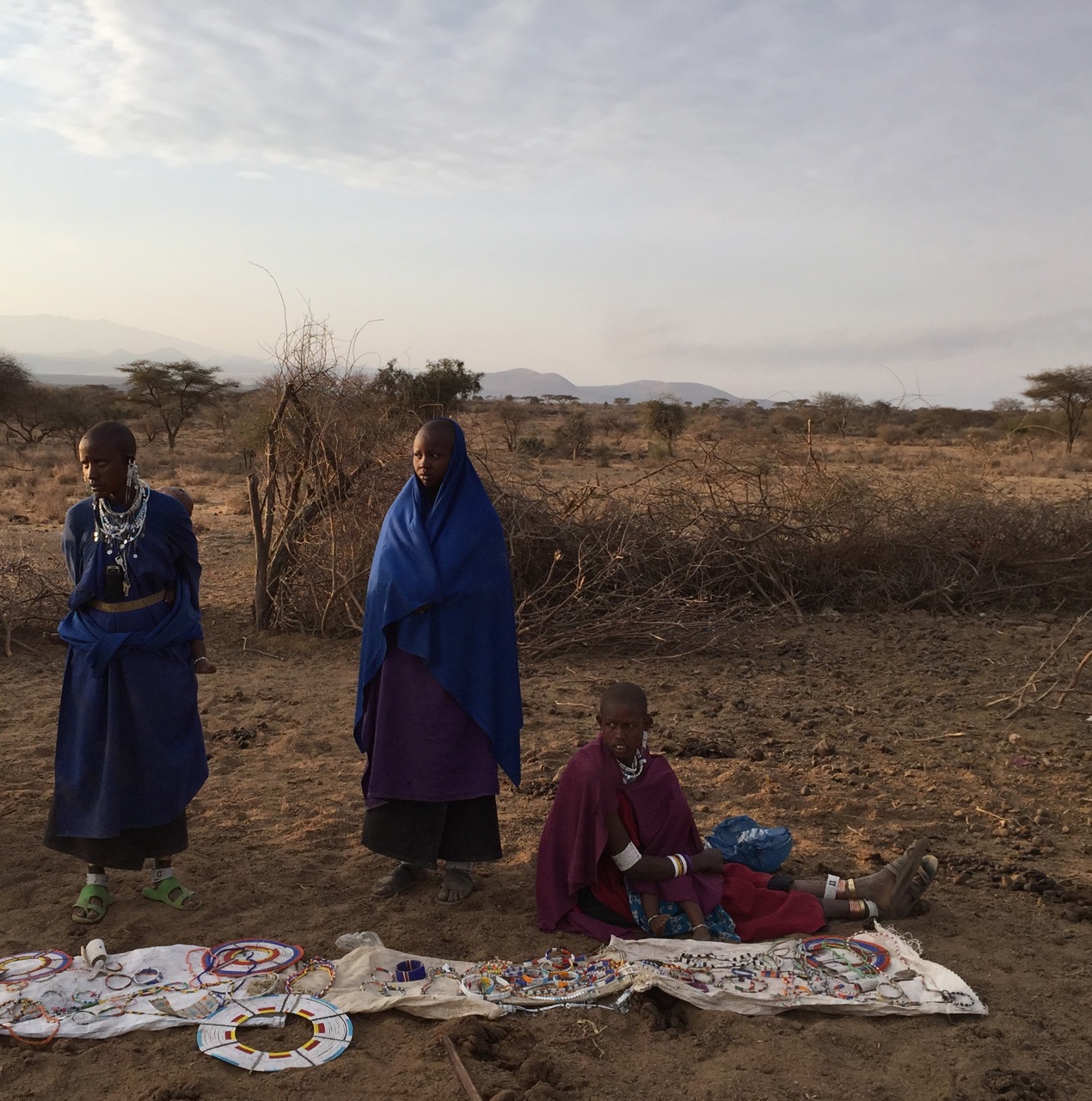 Masai women display their handmade beaded jewelry for sale to our tour group after our visit.