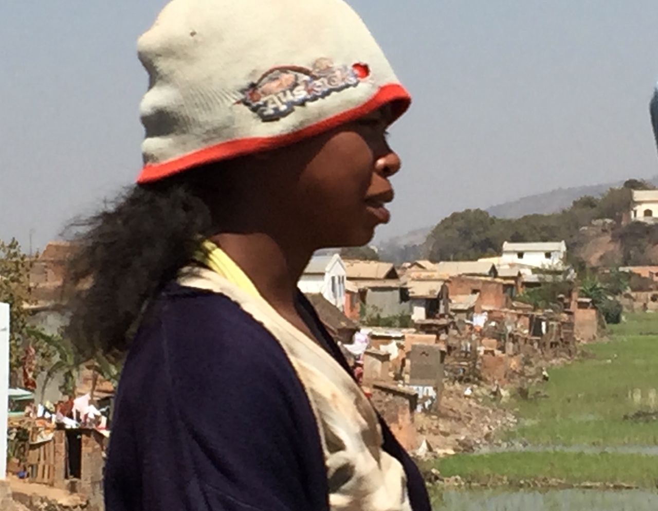 A young Malagasy woman walks along the road from the Antananarivo, the capital city of Madagascar to the airport, through congested traffic and terrible air pollution.