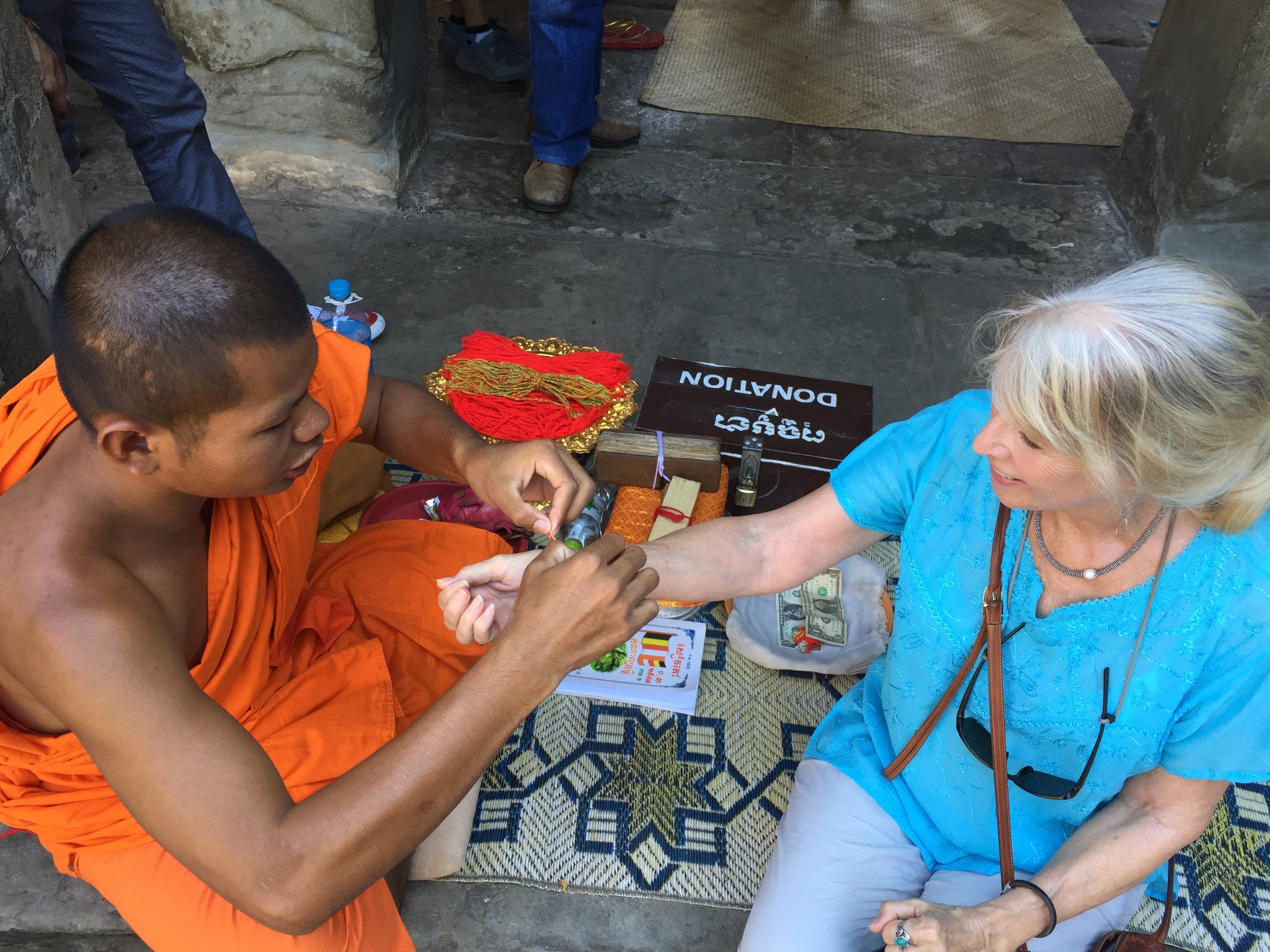 Receiving a blessing and a woven bracelet from a Buddhist monk at Angkor Wat, Cambodia.