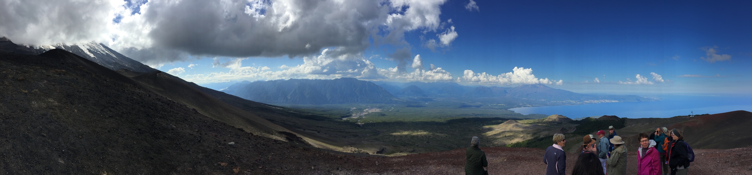 Osorno Volcano at the left, partly obstructed by clouds, in Chile's southern Andes. On the right are members of my tour group.