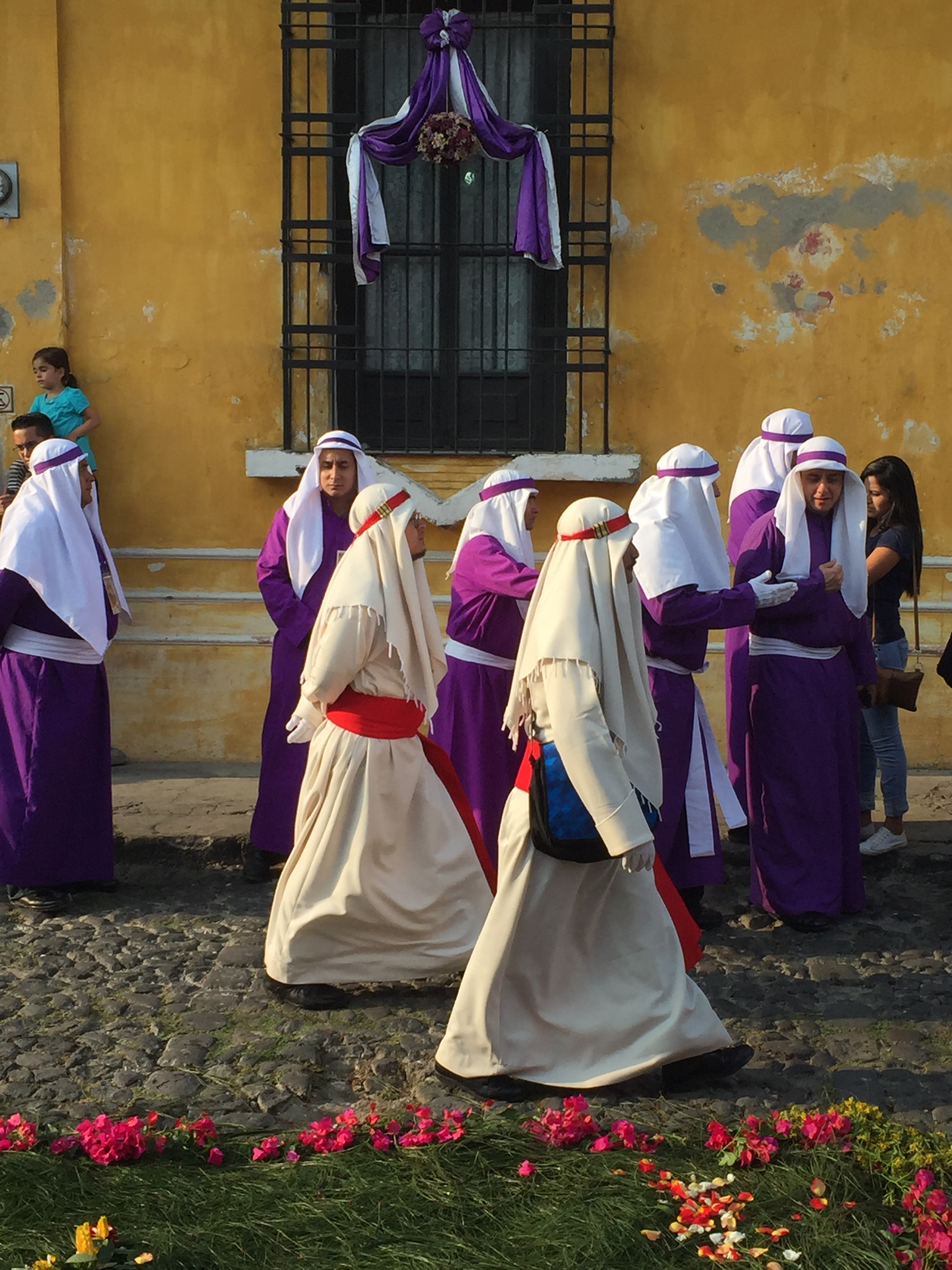 Robe clad processioners walking along the cobblestone streets, next to flower-strewn sawdust carpets.