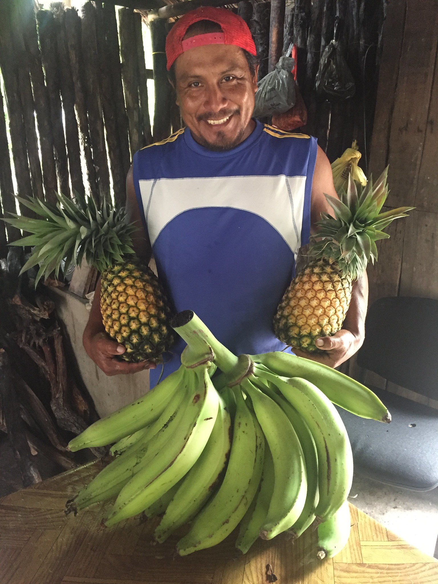 Smiling from ear to ear, Montiel displays recently-harvested pineapples and plantains