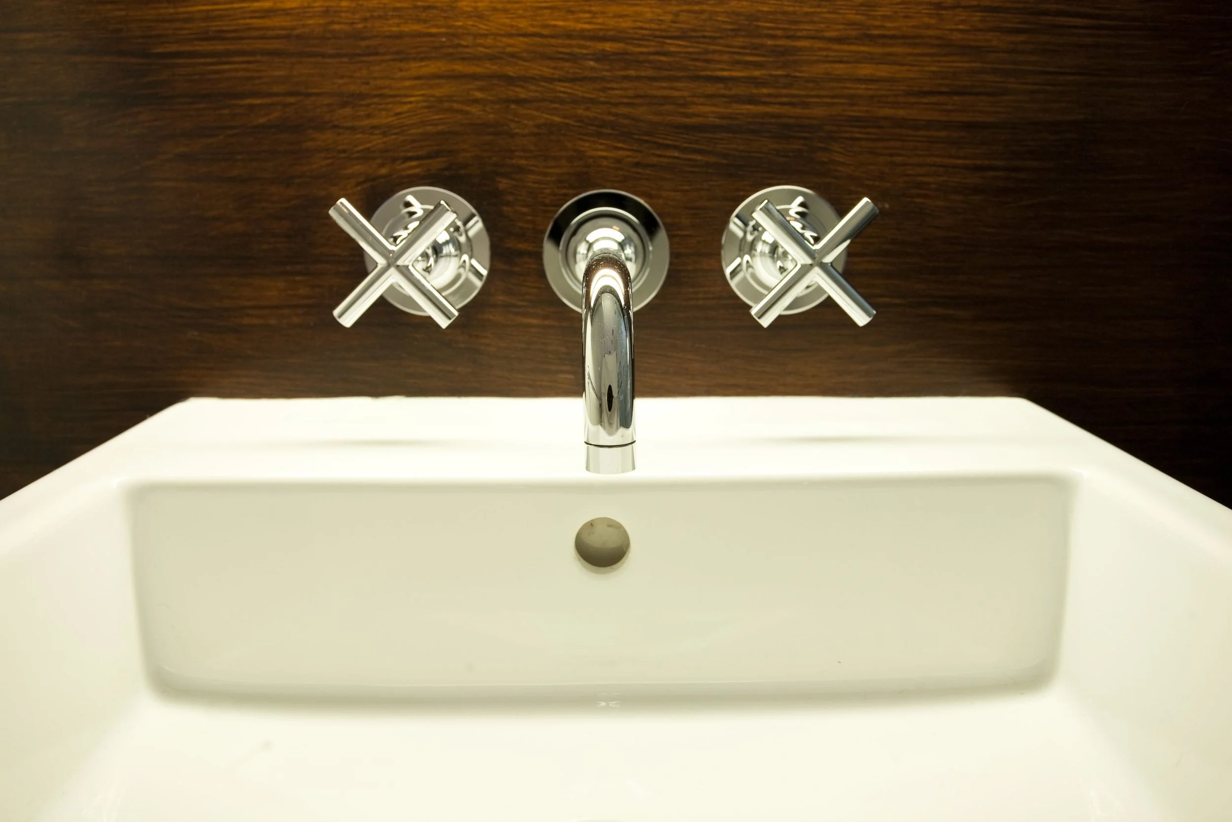 Detail of teak wood wall detail, under cabinet lights and wall-mounted faucet.