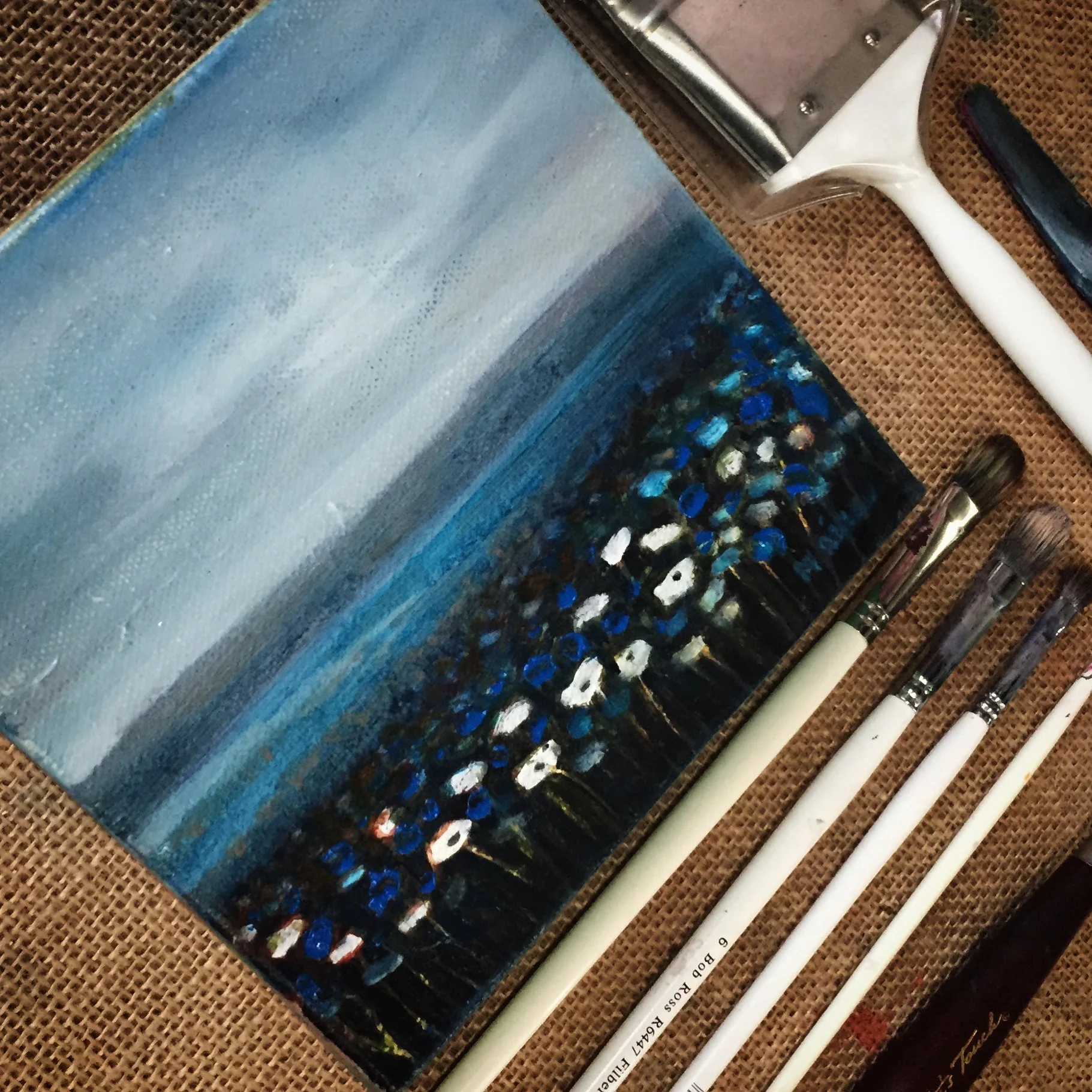 Painting tools with a flower field study in oil by Maria Rizzo.