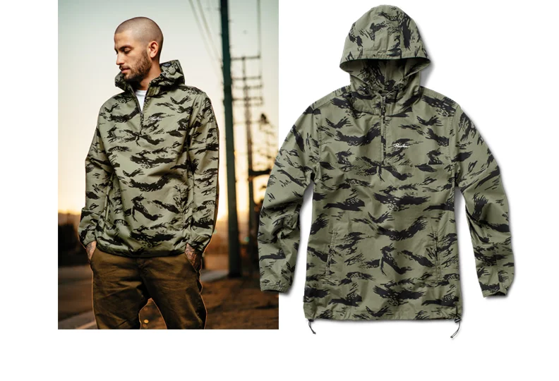  PRIMITIVE® ENDEAVOR ANORAK - Mid-weight cotton poplin with custom camo print and 1000mm DWR coating. Funnel-neck anorak with welt pockets and bungee toggles at hood and waist. (Shown in Olive Camo)&nbsp;[o] Oliver Barton 