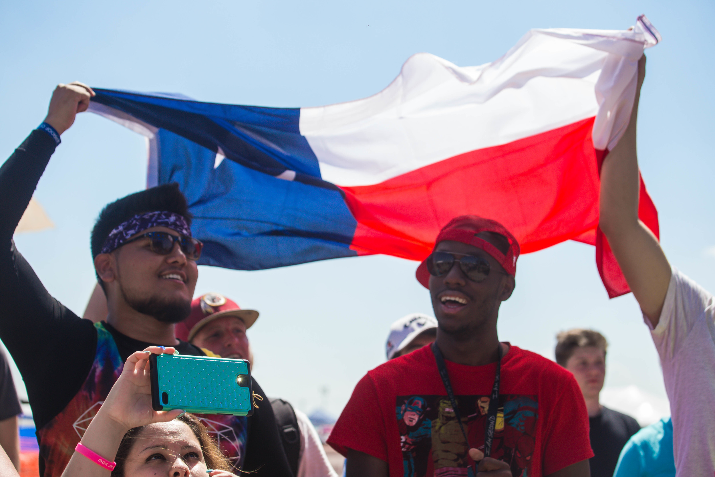 fans shield themselves from the sun with a Texas flag