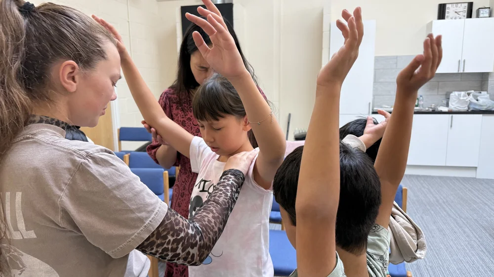Maci Hamby praying with children at Liberty Worship Centre in Cambridge, UK