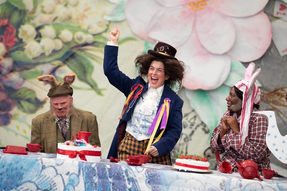 The Mad Hatter raises his right hand as he laughs triumphantly, whilst the March Hare and the Dormouse look on afraid. Photo by Ali Wright.