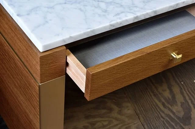 Detail shot of the Castaic desks in fumed white oak with brass hardware and Carrara marble top. The solid wood drawers utilized integrated drawer slides and a fabric wrapped aluminum bottom panel to reduce their overall height. This helped make room 