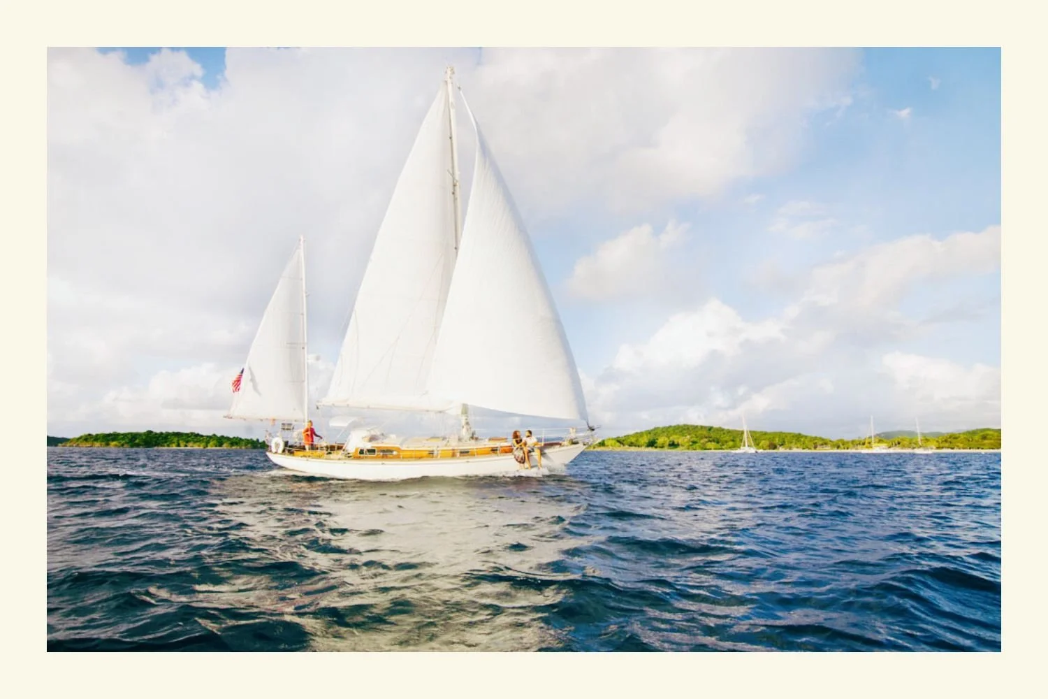 A photograph in a white frame of a sailboat with white sails from Cimarron Yacht Charter in the Caribbean, St. John.