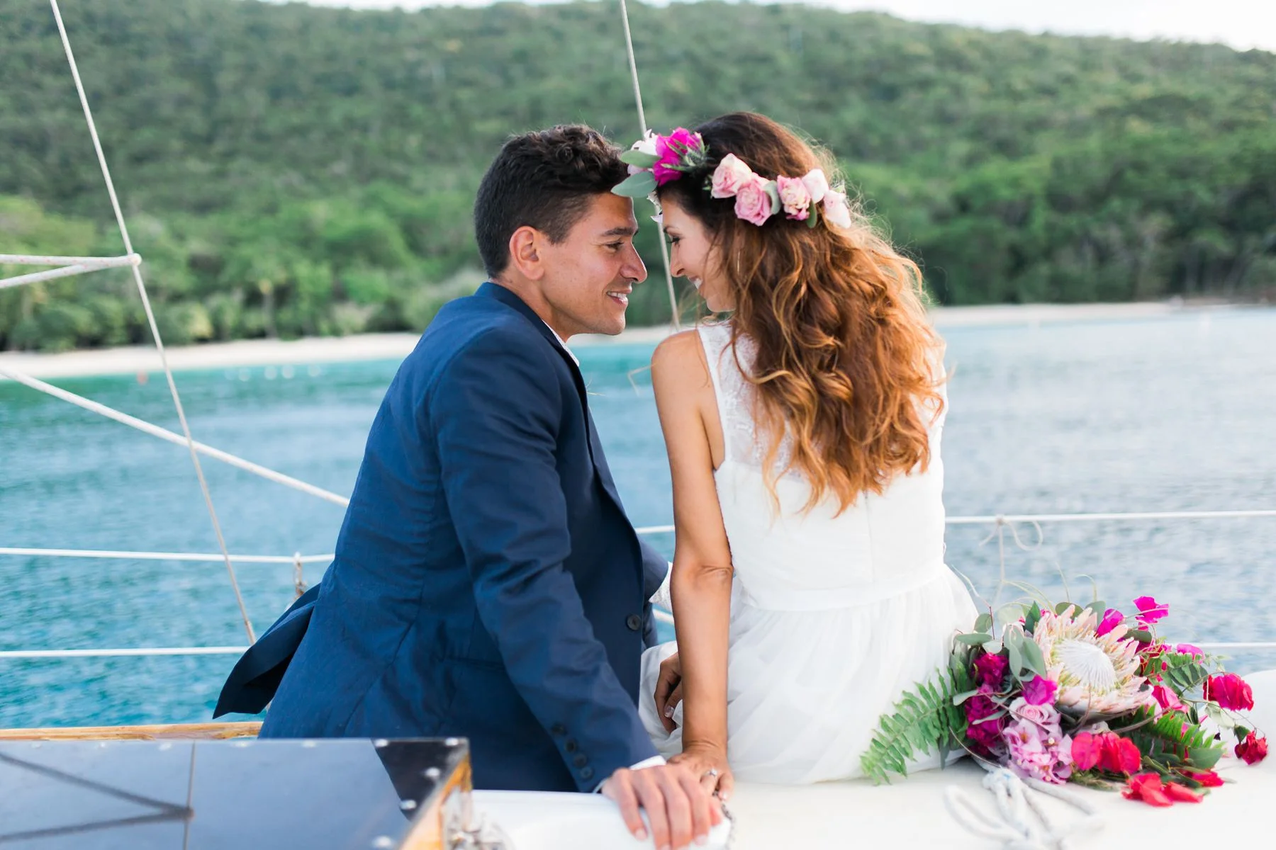 A bride and groom kiss on the bough of Cimarron, a sailboat on St John, USVI.