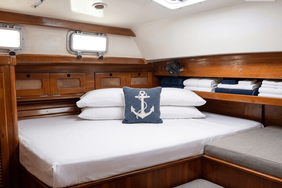 The cabin of an overnight charter with white sheets and wooden trim.