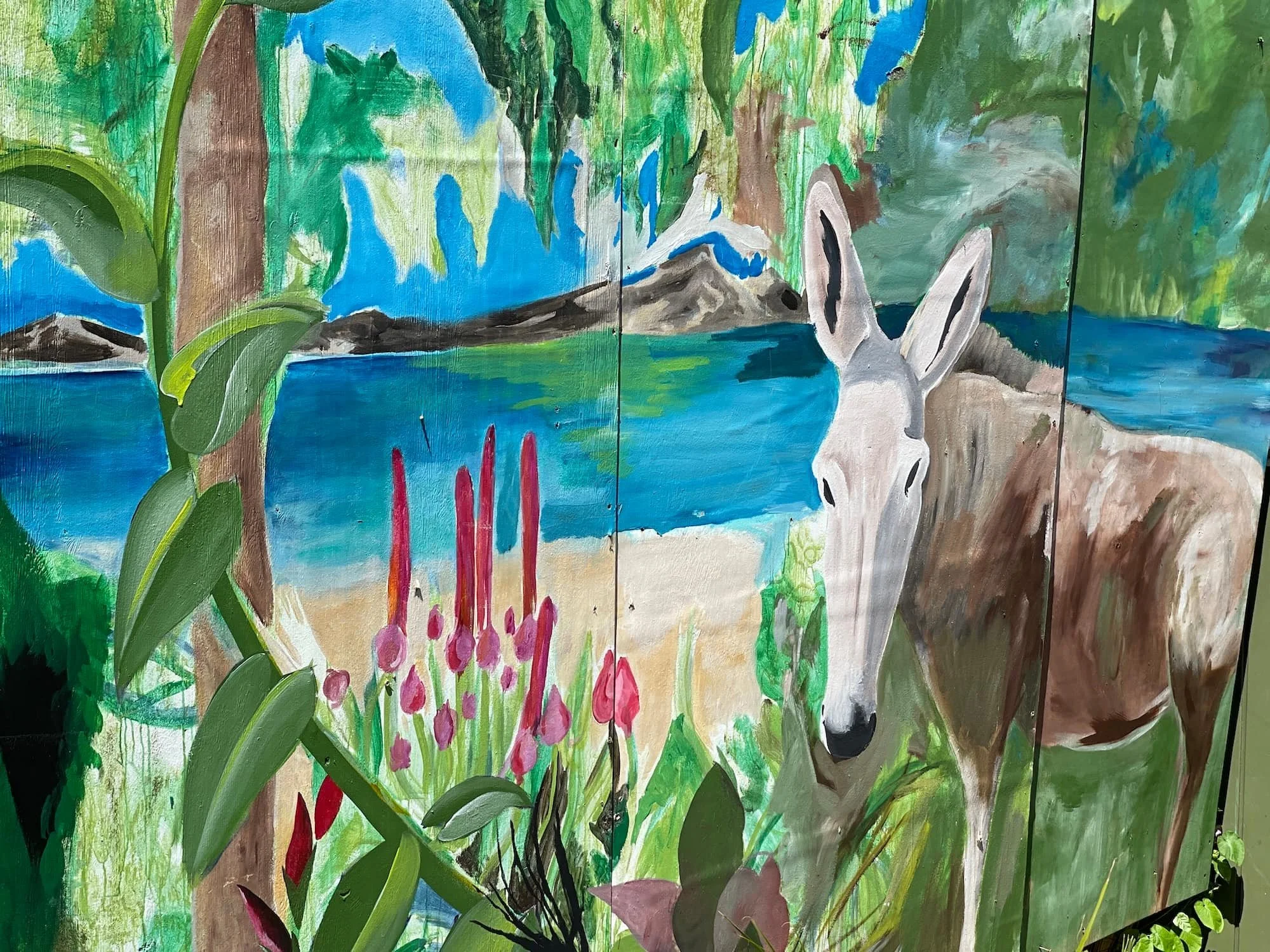 A colorful painting of a outdoor scene with a white and black hare in a green landscape with water, trees, pink flowers, and a mountain in the background.