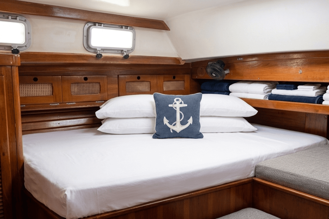 The sleeping quarters of Cimarron Yacht Charters for overnight sails, crisp white sheets and wooden fixtures for an unforgettable night in St John, USVI.