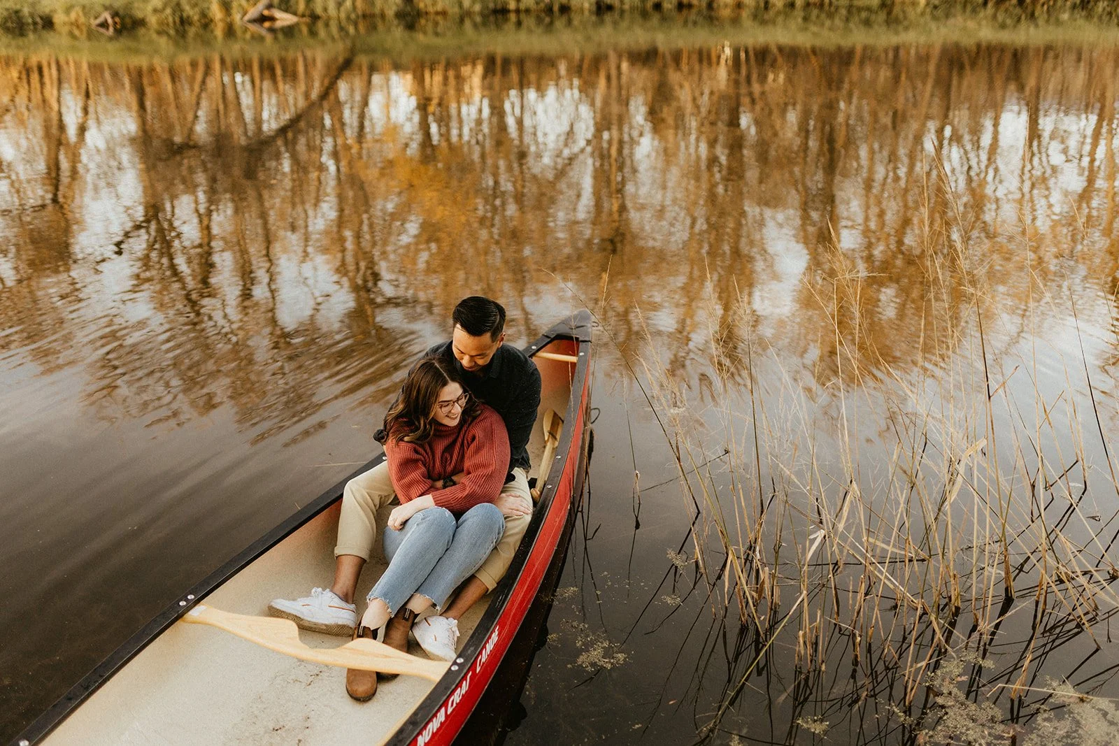 Couple sitting together in a canoe during a cozy engagement session at La Barriere Park in Winnipeg