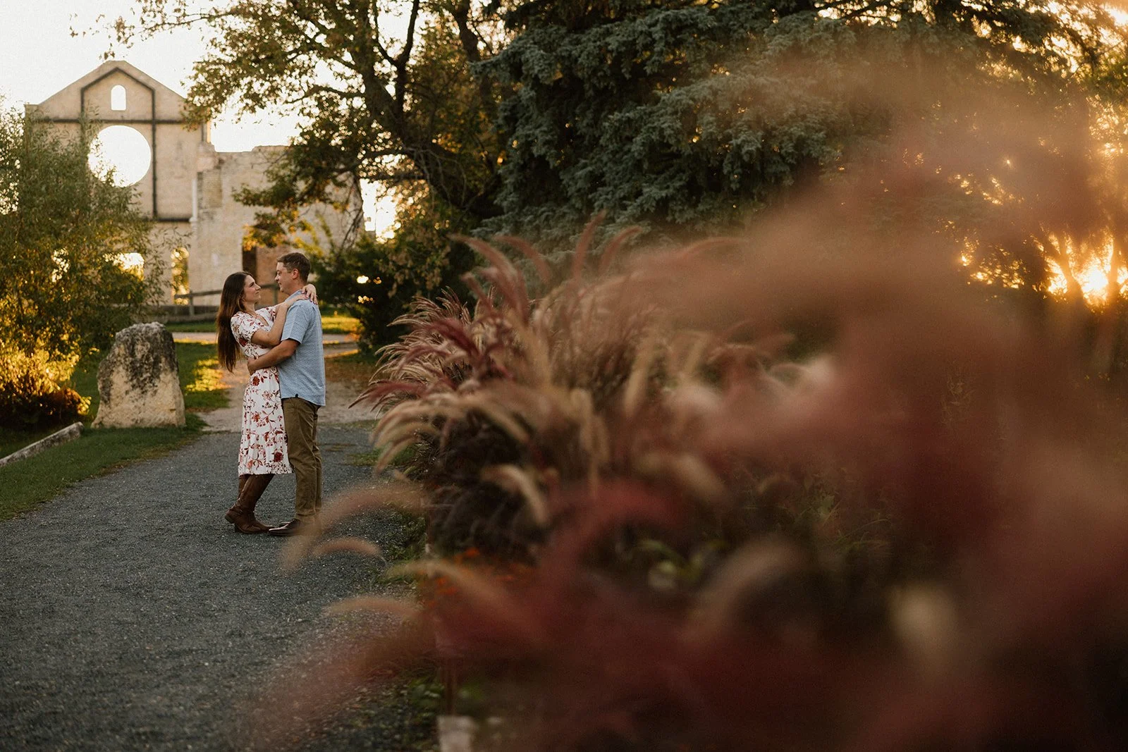  Couple embracing at St. Norbert ruins during a sunset engagement session in Winnipeg with warm golden light 