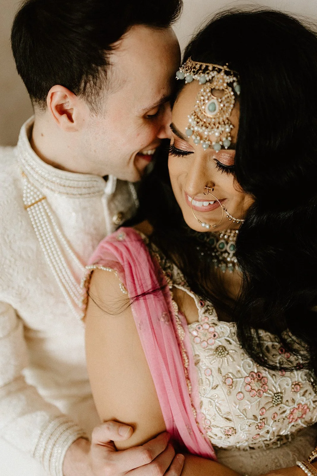  Couple sharing a close moment at May 11 Studio during a pre wedding photoshoot in Winnipeg, with traditional South Asian bridal jewellery and headpiece visible in detail 