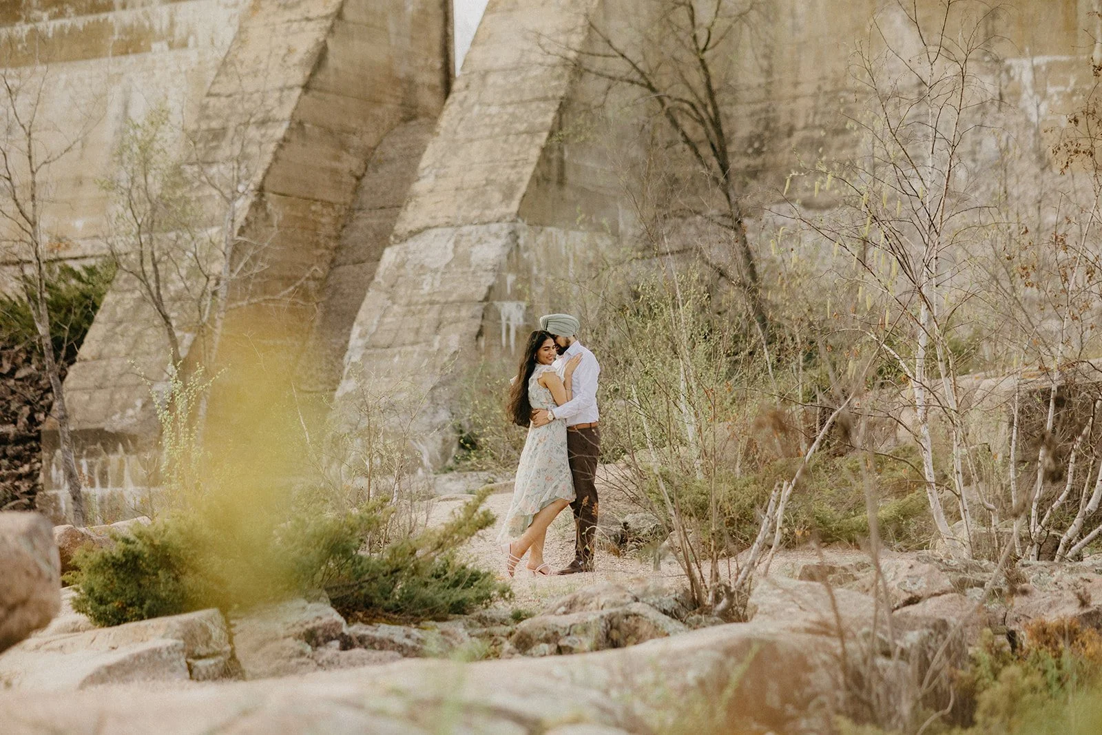  Couple embracing during a pre wedding photoshoot at Pinawa Dam in Manitoba, surrounded by natural rock and greenery in a scenic outdoor setting 