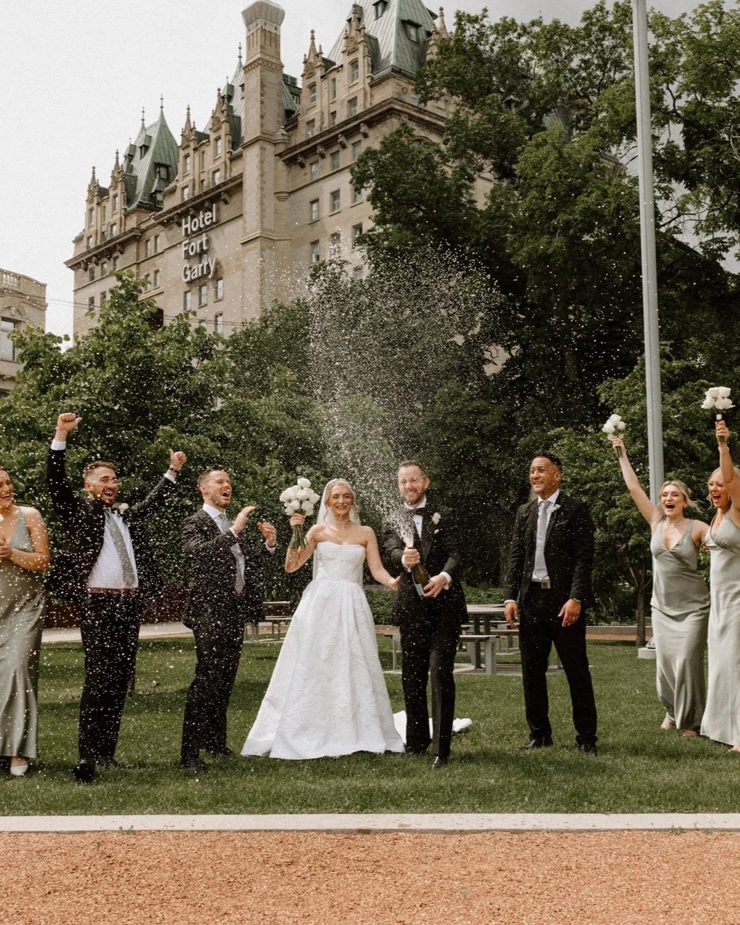  Wedding party celebrating outside Upper Fort Garry with the Fort Garry Hotel in the background, Winnipeg 