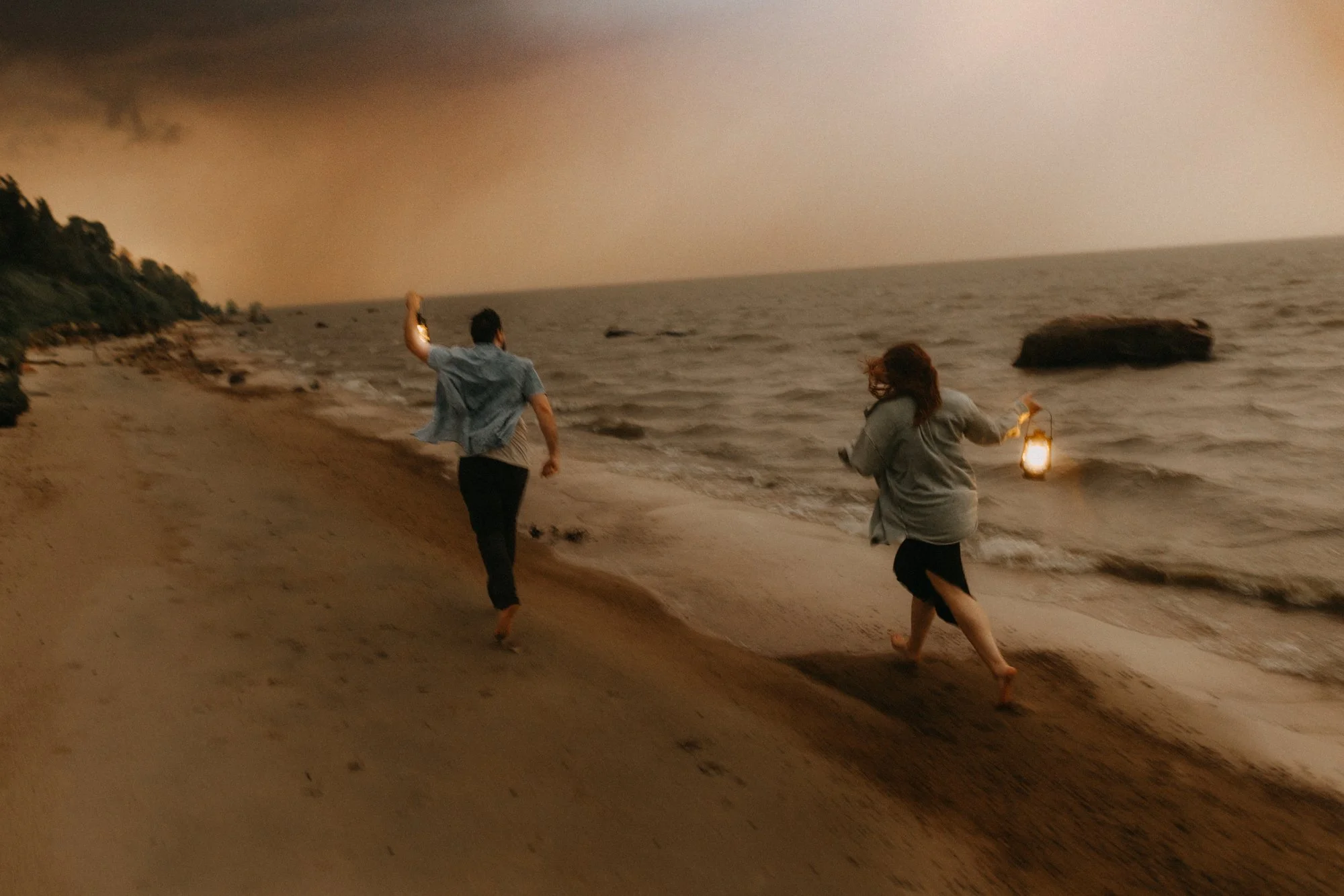 Couple running along the beach at sunset during a romantic engagement session in Manitoba near Winnipeg