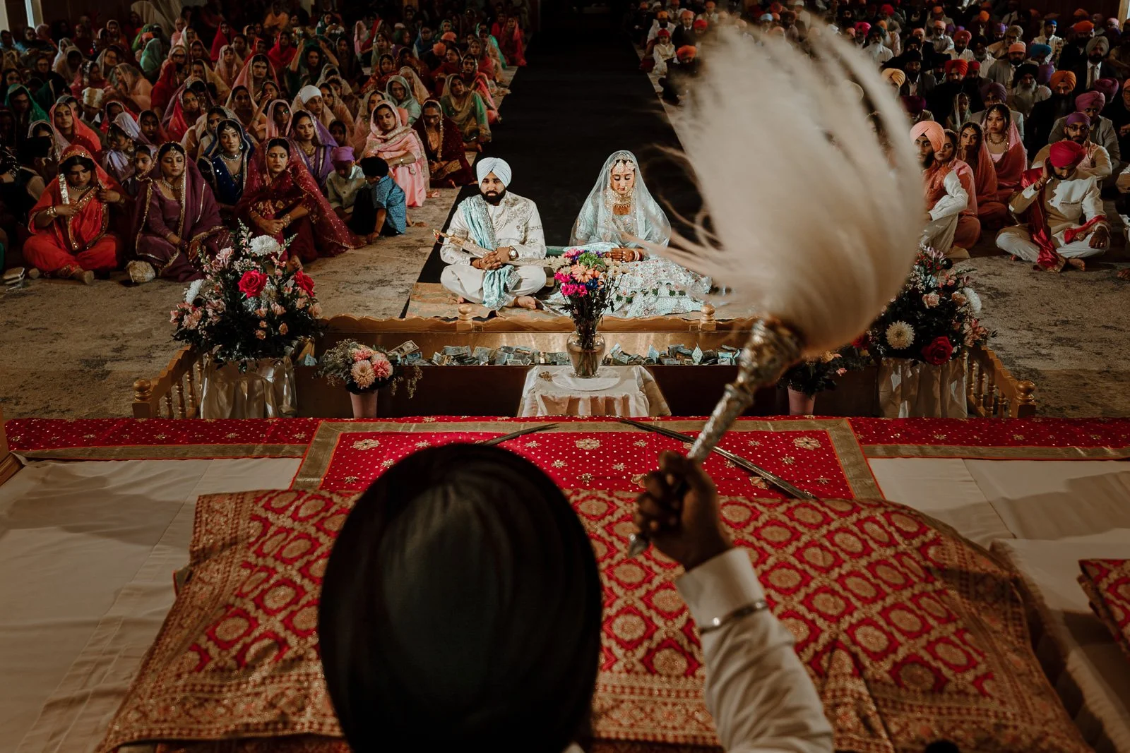 Sikh Anand Karaj wedding ceremony in Winnipeg with bride and groom seated during the ceremony surrounded by guests