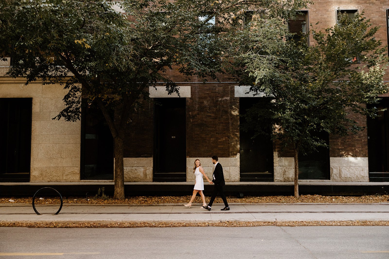 Couple walking together along a street in the Exchange District during an engagement session in Winnipeg