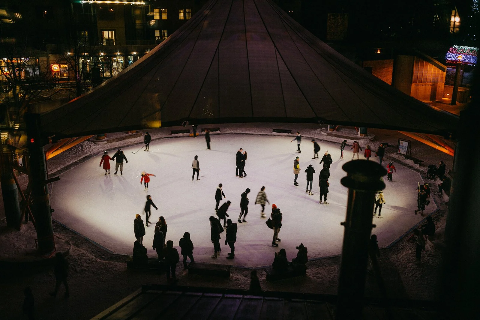 Couple standing together on the skating rink at The Forks during a winter engagement session in Winnipeg at night