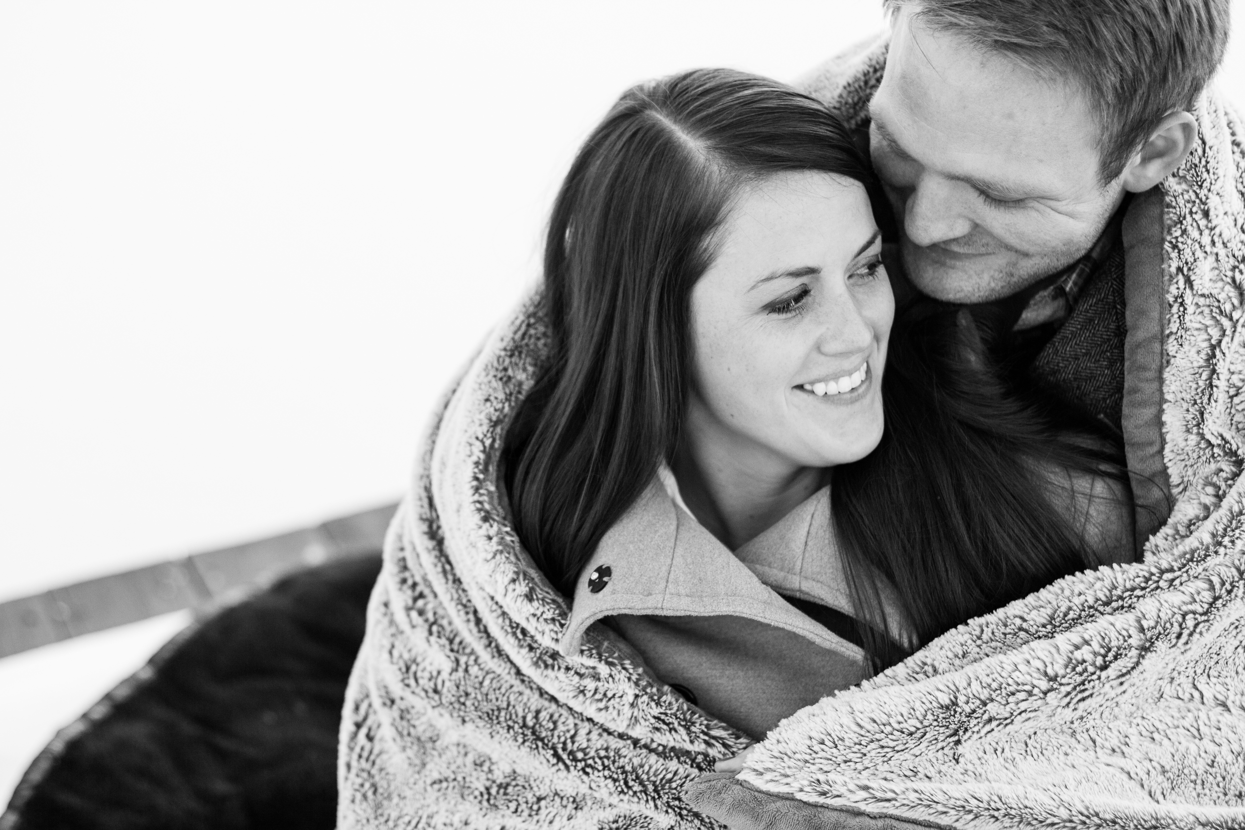 couple cuddling under blanket for engagement shoot