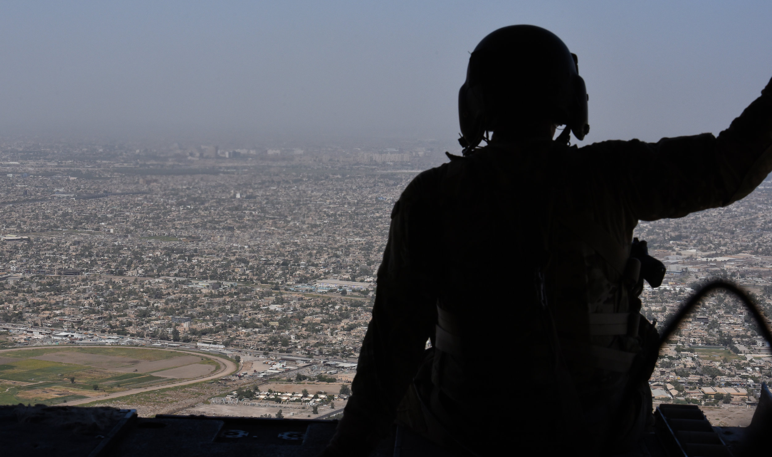 A U.S. soldier looks out over Baghdad, Iraq from the rear of an American CH-47 Chinook helicopter.