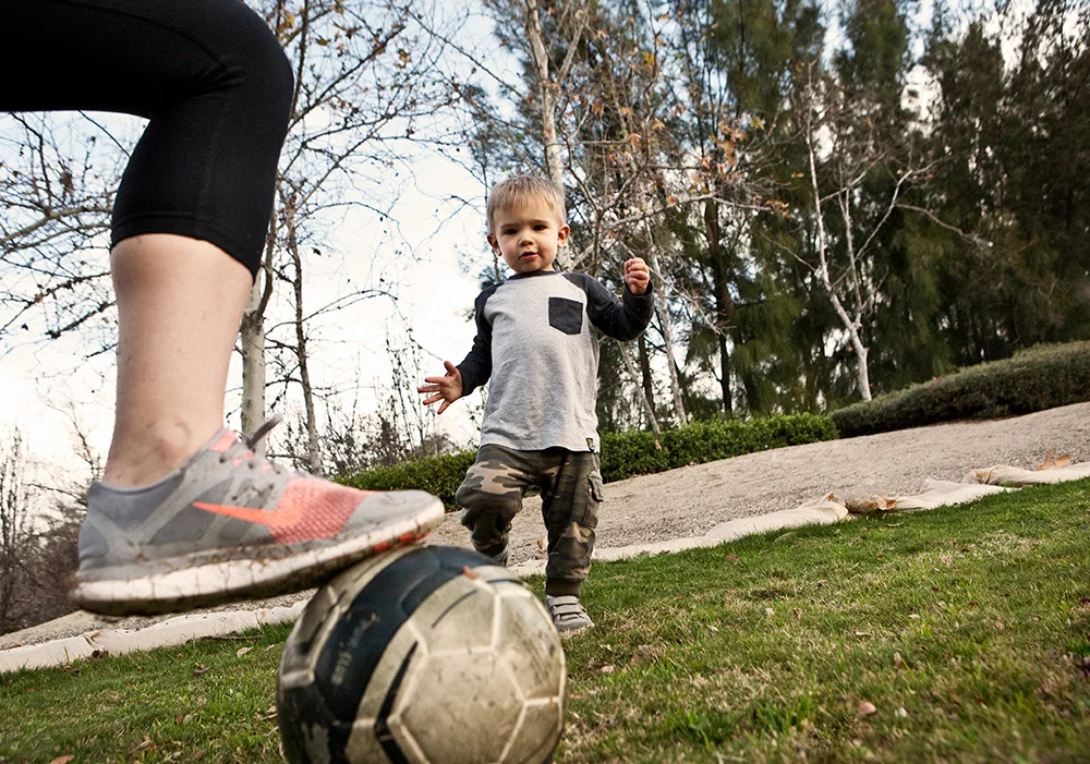 Ryan and mom kick the soccer ball around.