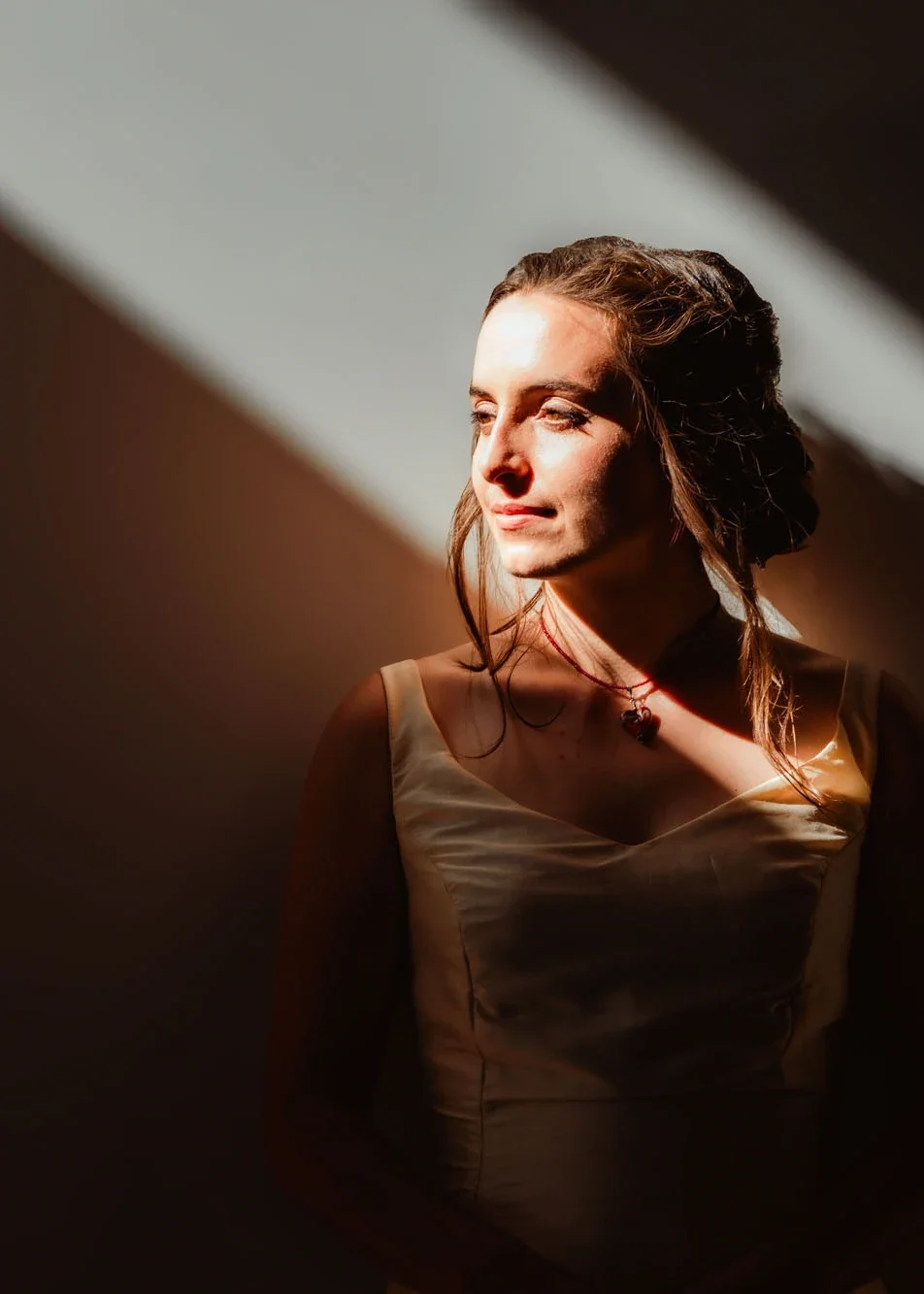 Dramatic bridal portrait with golden sunlight streaming across the bride’s face and elegant cream gown. Joyful and serene moment captured by Abbotsford, British Columbia wedding photographer.