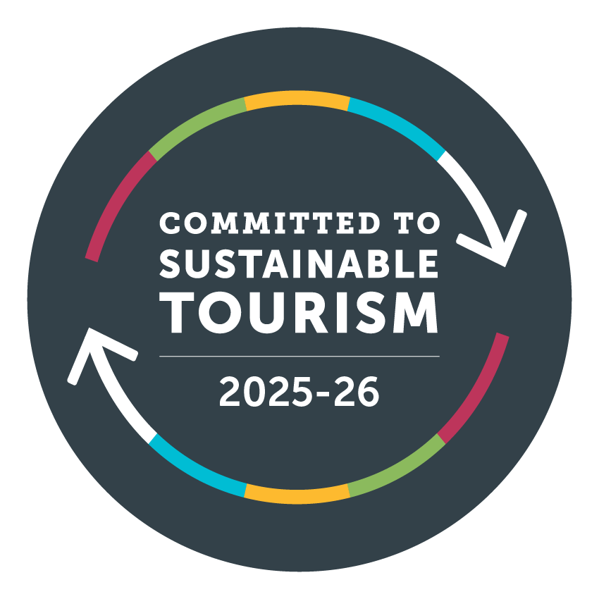 Circular graphic with the text 'Committed to Sustainable Tourism 2025-26' and colorful segmented arrows indicating sustainability commitment.