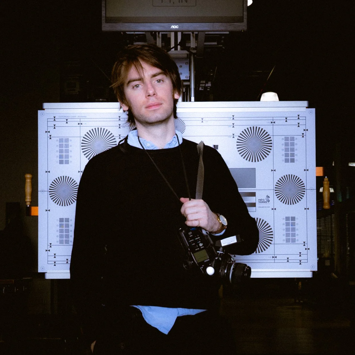 Filmmaker James Gallagher stands with camera and focus chart.