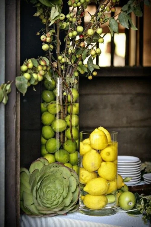 4. FRUITFUL CENTERPIECES BY CONFRARIA DAS TRUFAS: Create a fresh, brightly colored table with lemons and limes in water filled cylinder vases .