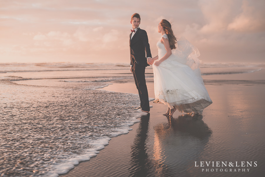 Bride and groom walking in the waves 