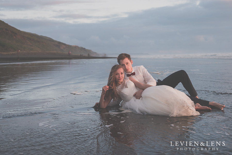 Bride and groom laying on the black sand