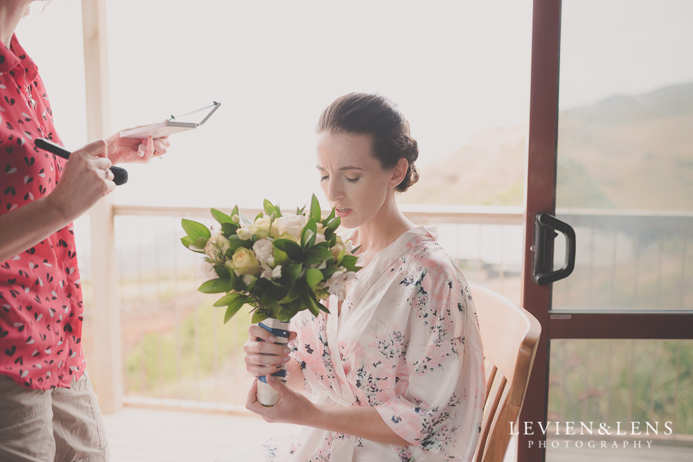 bride smell flowers Castaways Resort - Kariotahi beach wedding {Auckland lifestyle couples-engagement photographer}