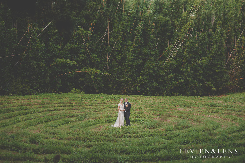 bride and groom intimate session Landscendt Tropical Garden {Auckland lifestyle wedding photographer} on big field in front of forest
