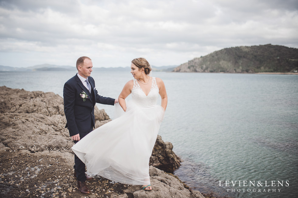 bride walking on rocks cliff - The Duke of Marlborough Hotel - Russel wedding {Northland-New Zealand weddings photographer} beach