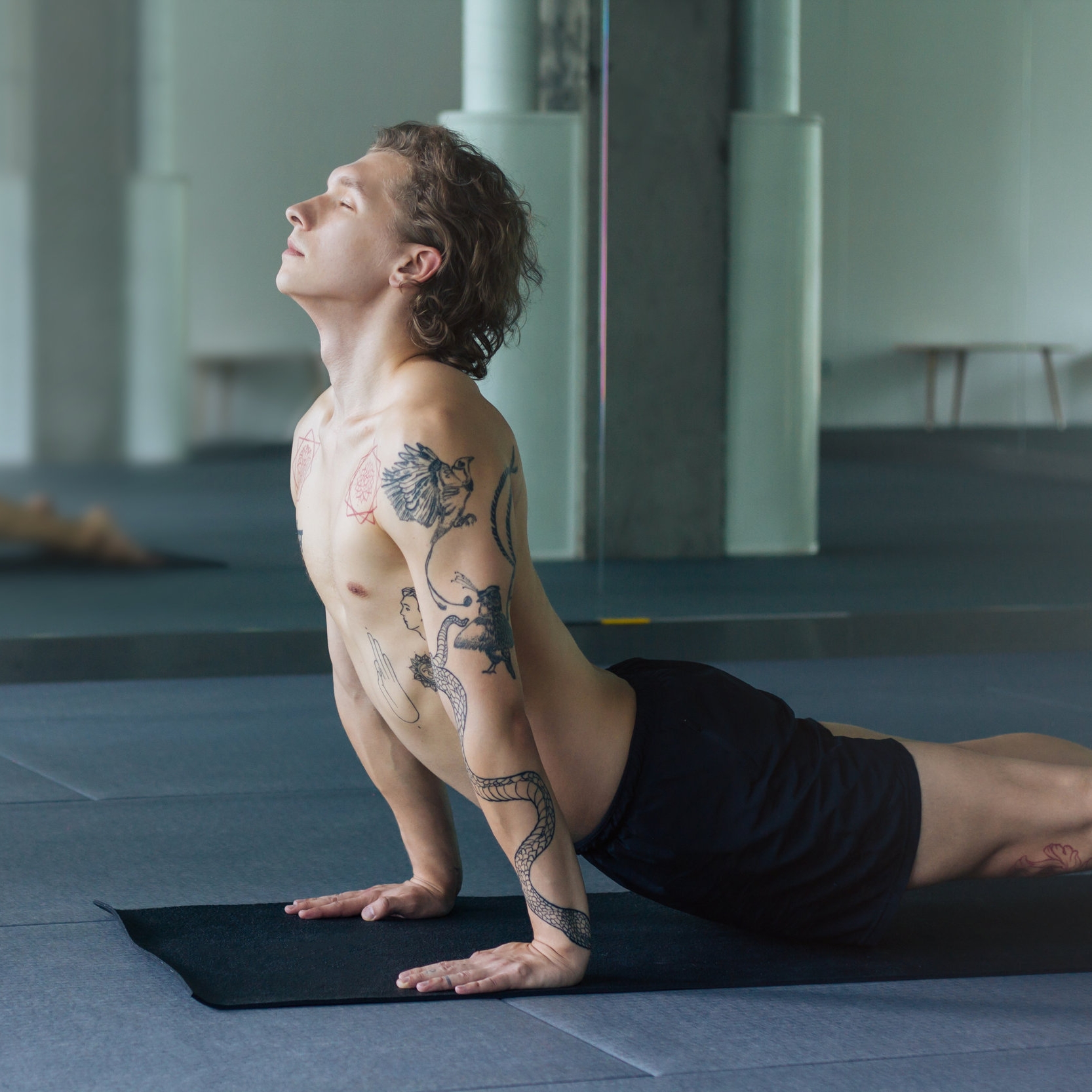 tattooed guy practices yoga