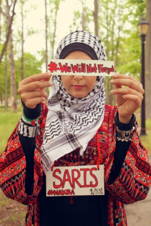 A student with SJP at the CUNY College of Staten Island wears a sign with the name of a Palestinian village that was depopulated in 1948 as part of the group’s “Nakba Week” programming. (CUNY College of Staten Island Students for Justice in Palestine)