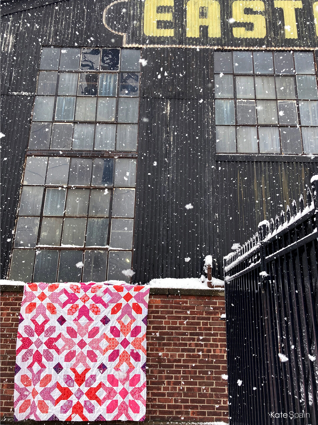 Blizzard Quilt hanging in front of brick wall