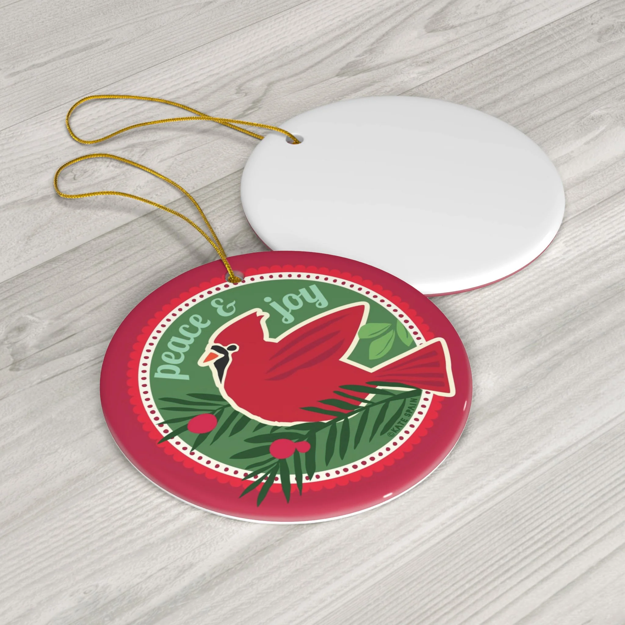cardinal bird peace and joy pine sprigs image on red and green background holiday christmas winter ornament 3 inch round porcelain ceramic front and back